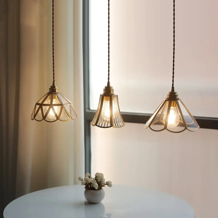 Suspension luminaire aureL avec trois lampes en métal doré et verre cannelé au-dessus d’une table blanche
