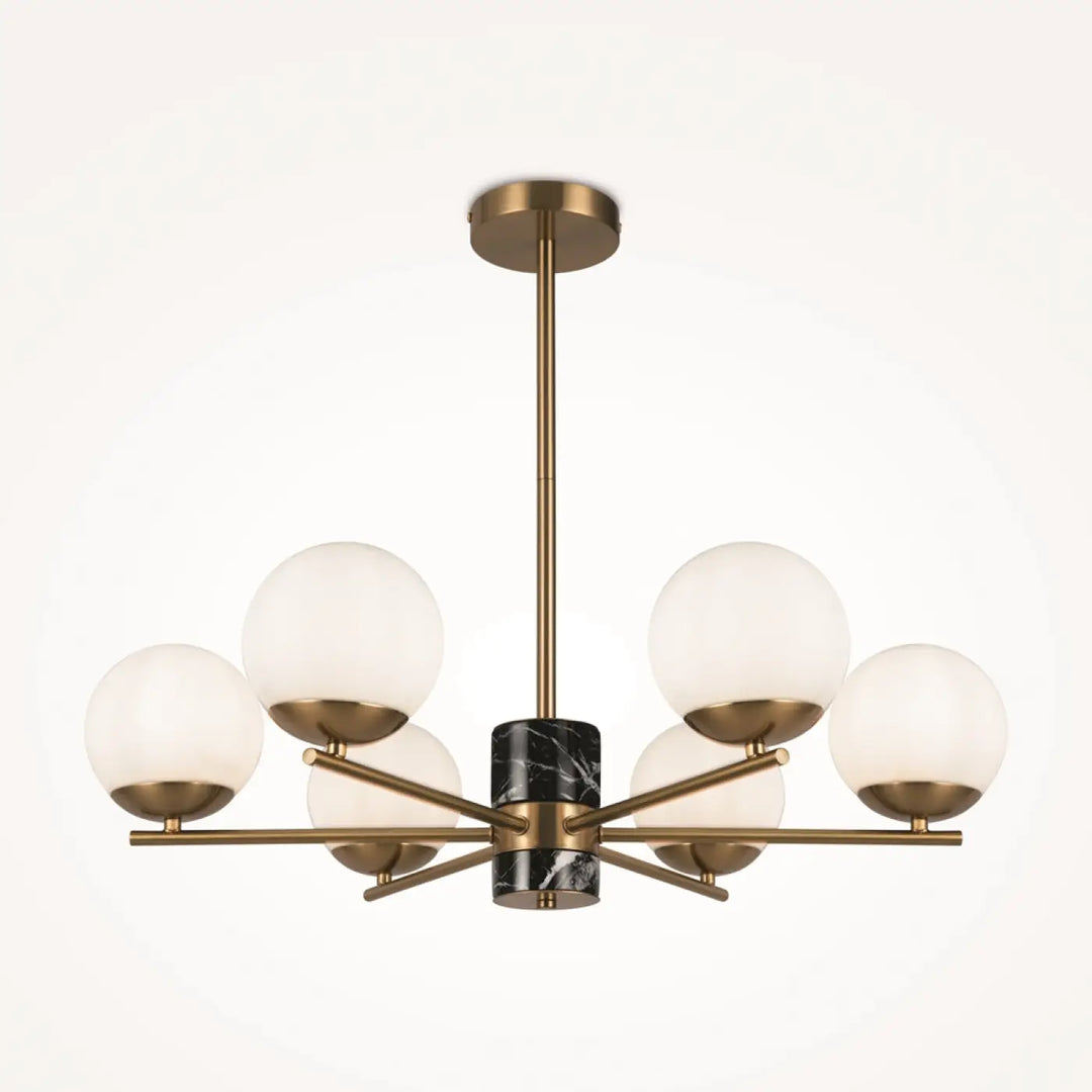 Suspension luminaire marble avec structure dorée, six globes en verre dépoli et accent central en marbre noir au-dessus d’une pièce