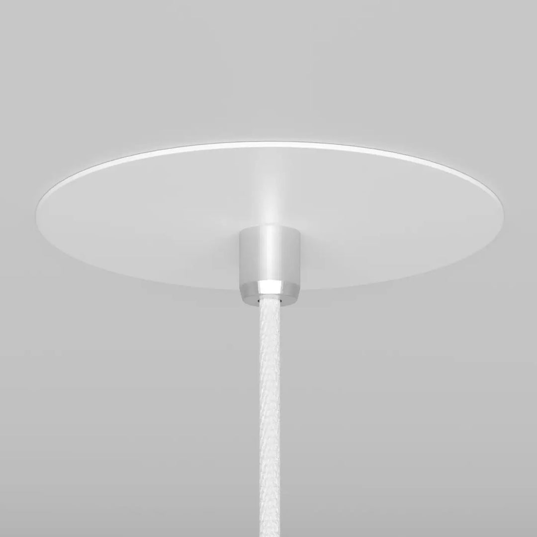 Suspension luminaire nevill cône étroit avec abat-jour circulaire blanc en acier noir au-dessus d’un espace minimaliste