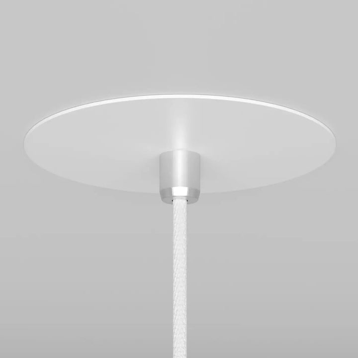 Suspension luminaire nevill cône étroit avec abat-jour circulaire blanc en acier noir au-dessus d’un espace minimaliste