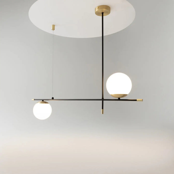 Suspension luminaire nostalgia linéaire en acier noir avec deux globes en verre opalin au-dessus d’une table