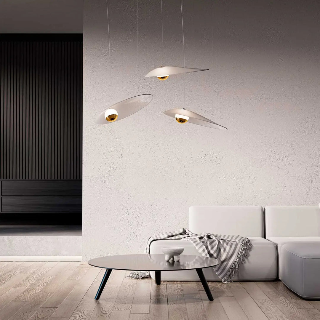 Trois suspensions luminaire oyster avec abat-jour blanc en forme de disque et centre doré suspendues au plafond