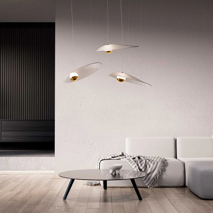 Trois suspensions luminaire oyster avec abat-jour blanc en forme de disque et centre doré suspendues au plafond