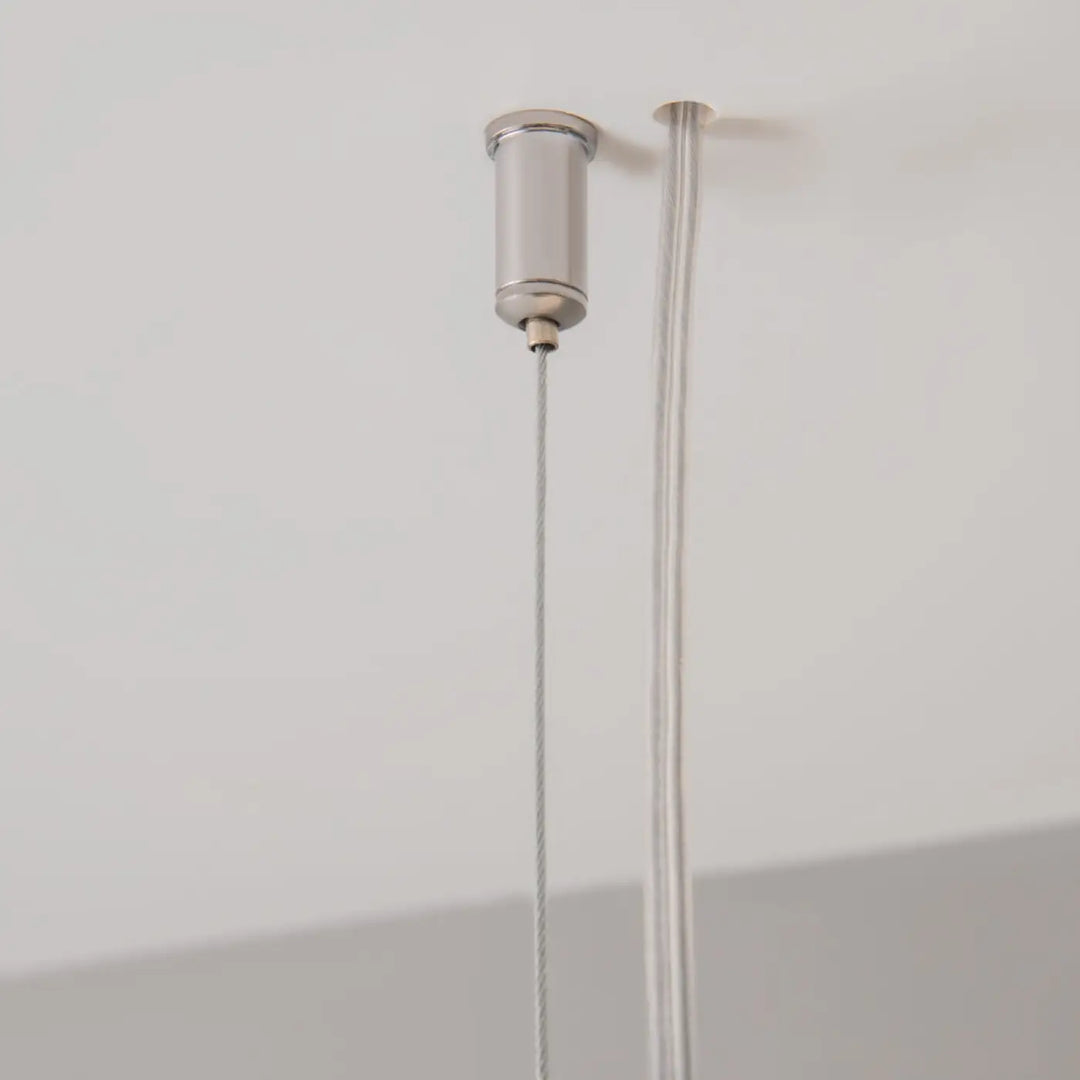 Suspension luminaire points barre linéaire argent cylindrique avec deux câbles fins points lumineux au-dessus d’un îlot