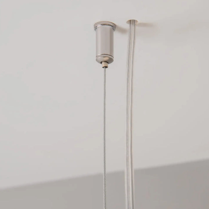 Suspension luminaire points barre linéaire argent cylindrique avec deux câbles fins points lumineux au-dessus d’un îlot