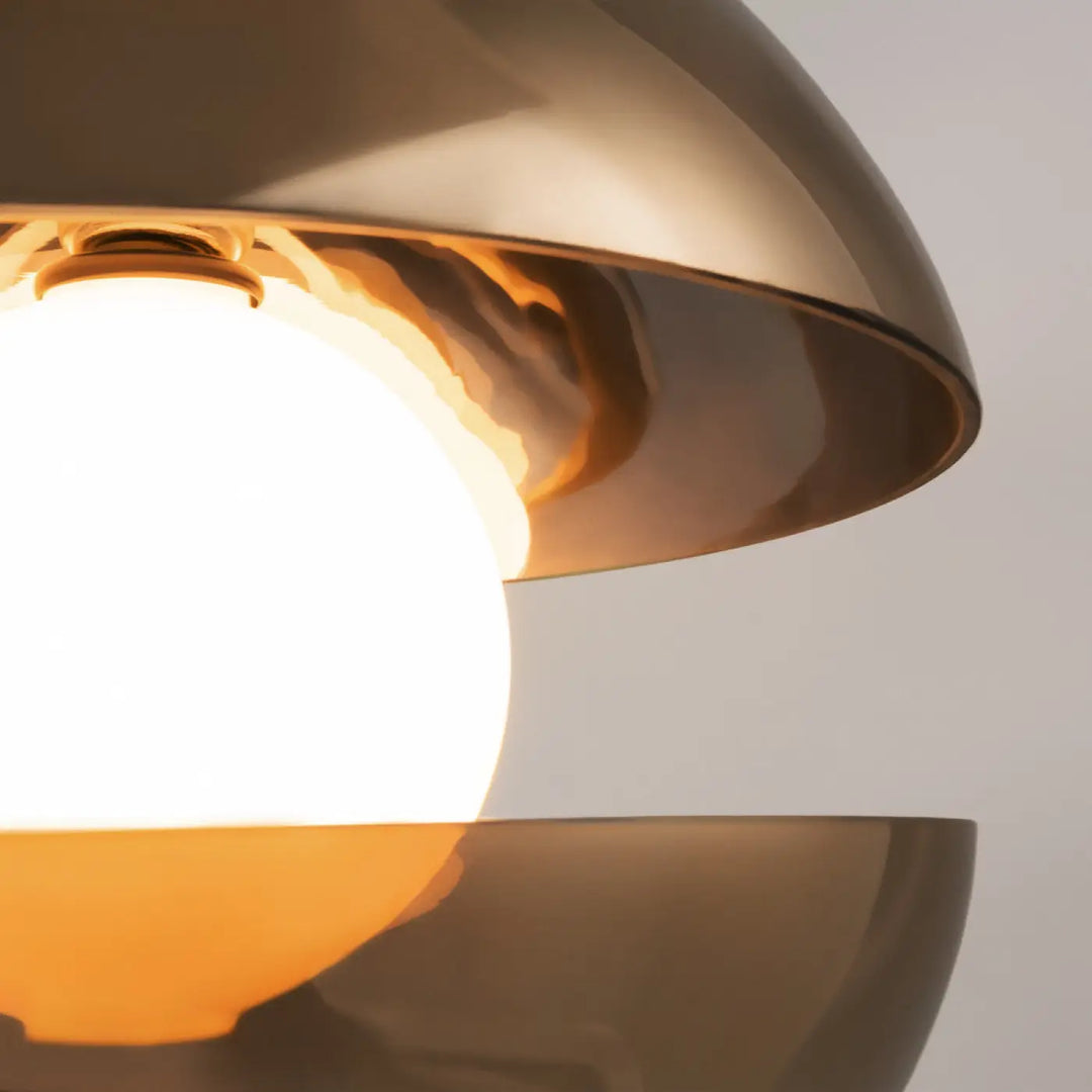 Suspension rebel en laiton brossé avec globe en verre ambré diffusant une lumière chaude au-dessus d’une table