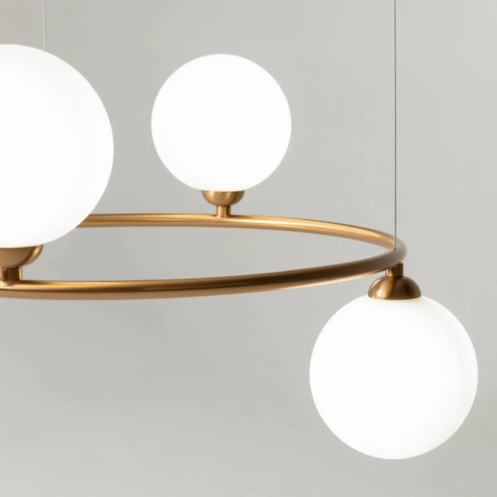 Suspension ring moderne avec trois sphères en verre dépoli blanc et cadre métallique doré touche art déco