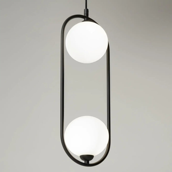 Suspension ring art déco avec structure métallique noire et deux globes en verre dépoli au-dessus d’un îlot