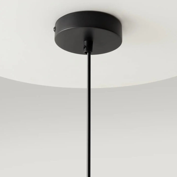 Luminaire suspension ring noir mat avec base cylindrique et tige fine au-dessus d’un îlot style art déco