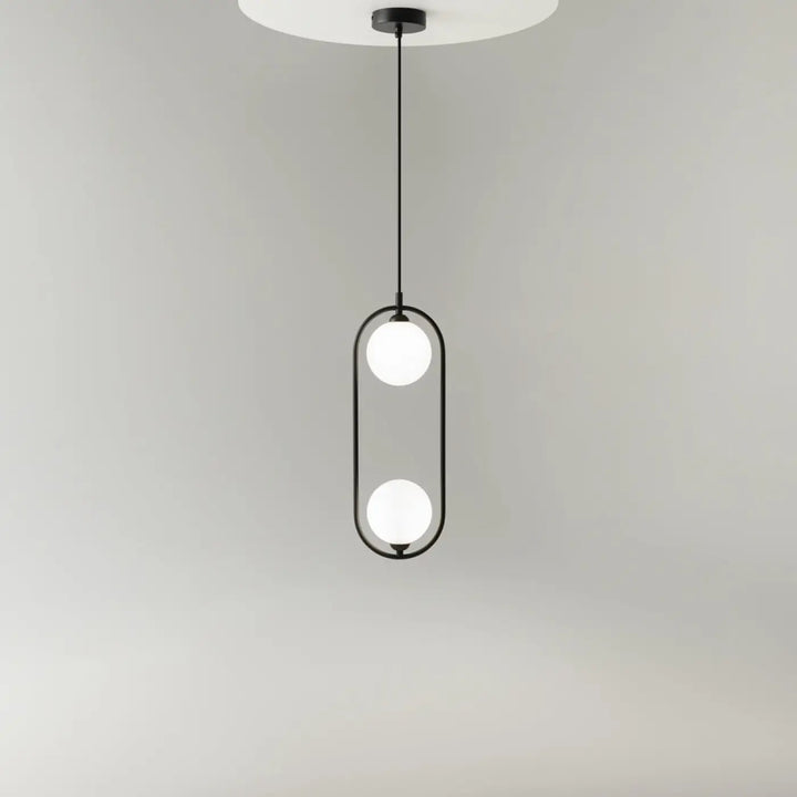 Suspension ring lumineux en métal noir avec deux globes en verre dépoli dans un cadre ovale art déco au-dessus d’un îlot