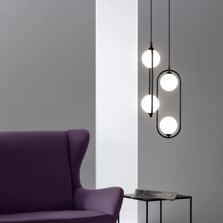 Suspension ring noire en métal avec quatre globes blancs lumineux en design vertical asymétrique art déco au-dessus d’un îlot