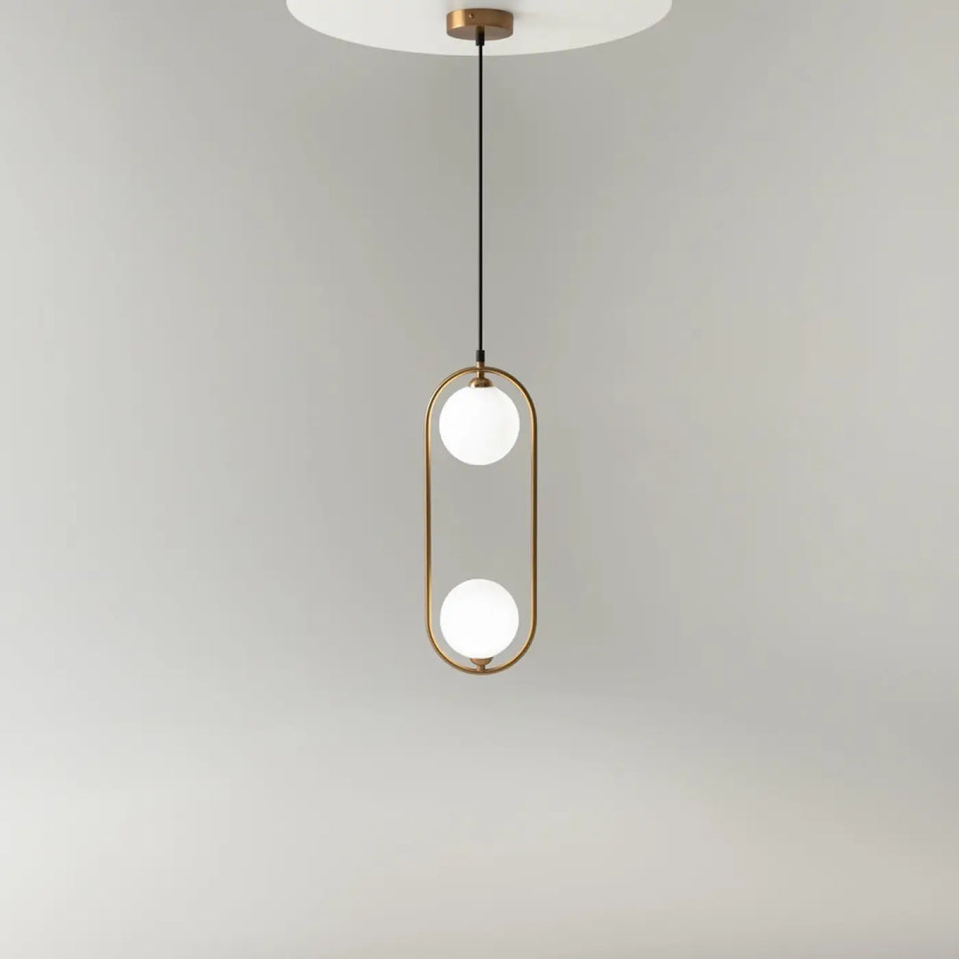 Suspension luminaire ring art déco avec deux globes en verre dépoli et structure en laiton au-dessus d’un îlot