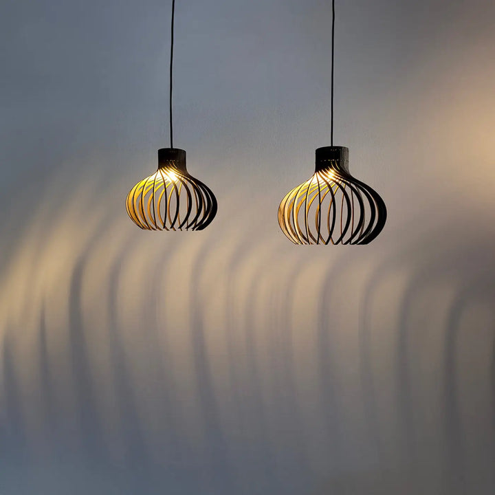 Deux suspensions noires en bois rinoz piatoni avec design tressé diffusant une lumière chaude pour cage d’escalier